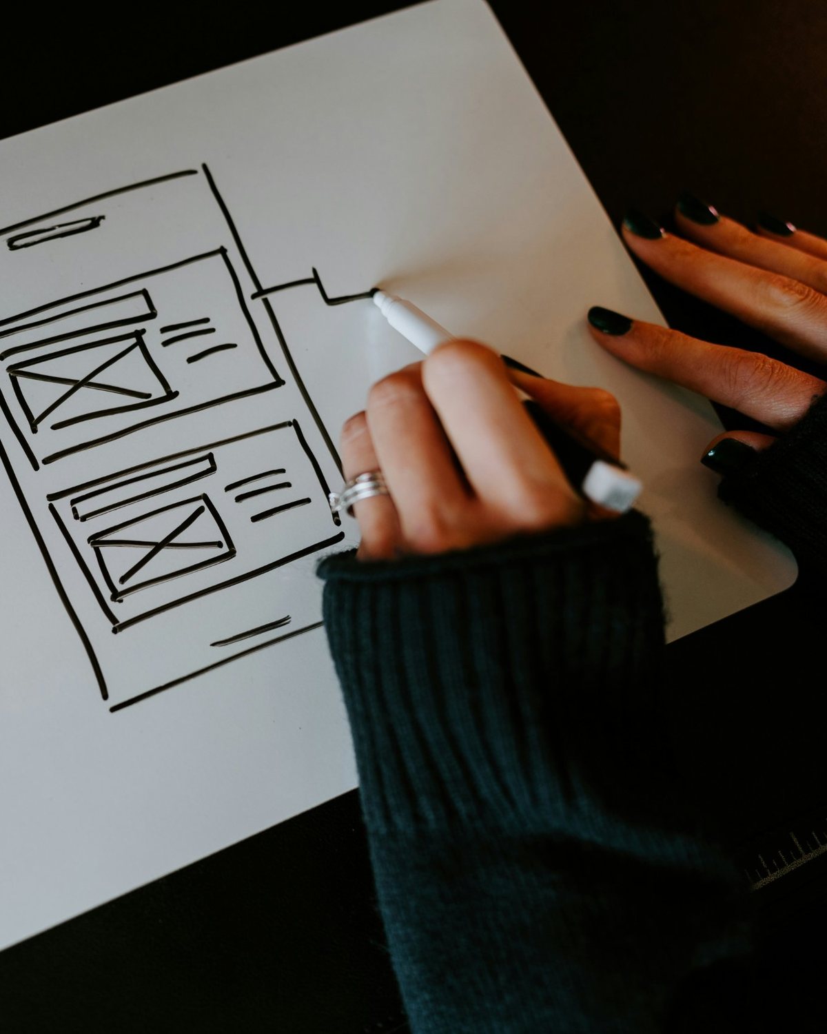 A hand sketching an app wireframe on a whiteboard